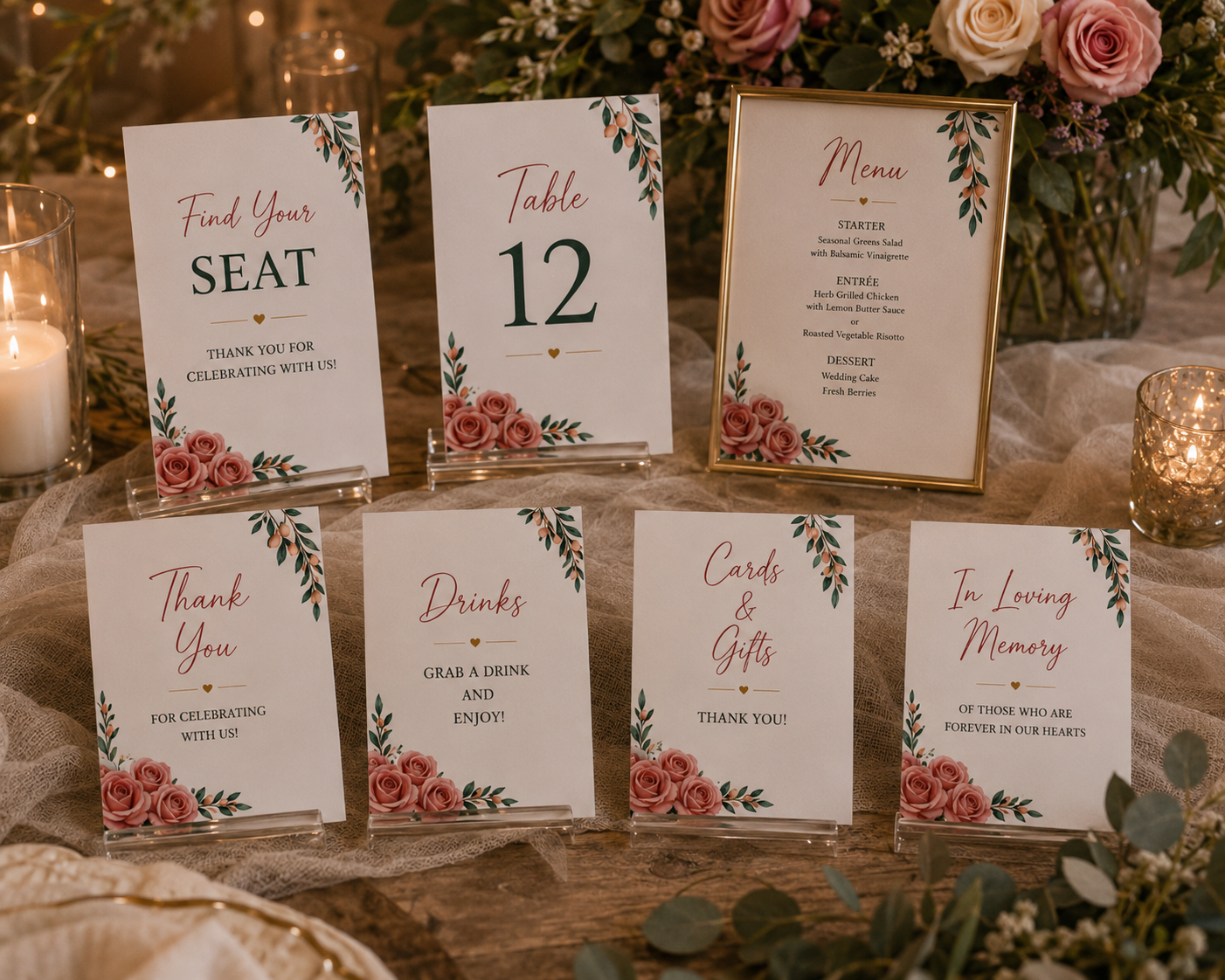Wedding reception table signs with pink floral borders displayed in clear acrylic block holders and a gold frame.