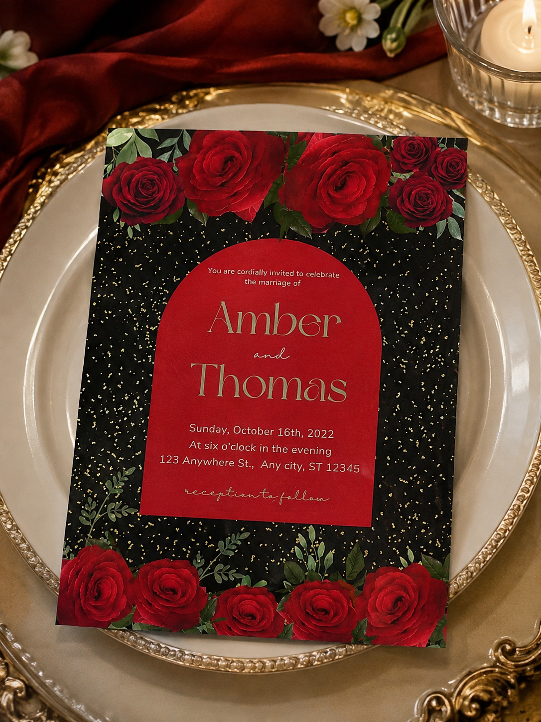 A woman holding a dramatic black wedding invitation featuring lush red roses, faux gold glitter, and a red arch text frame.